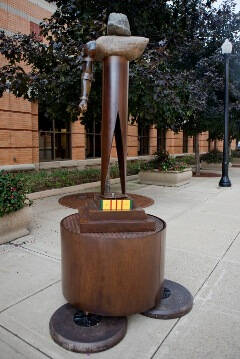 Sculpture that looks like an abstract person on a large round base.